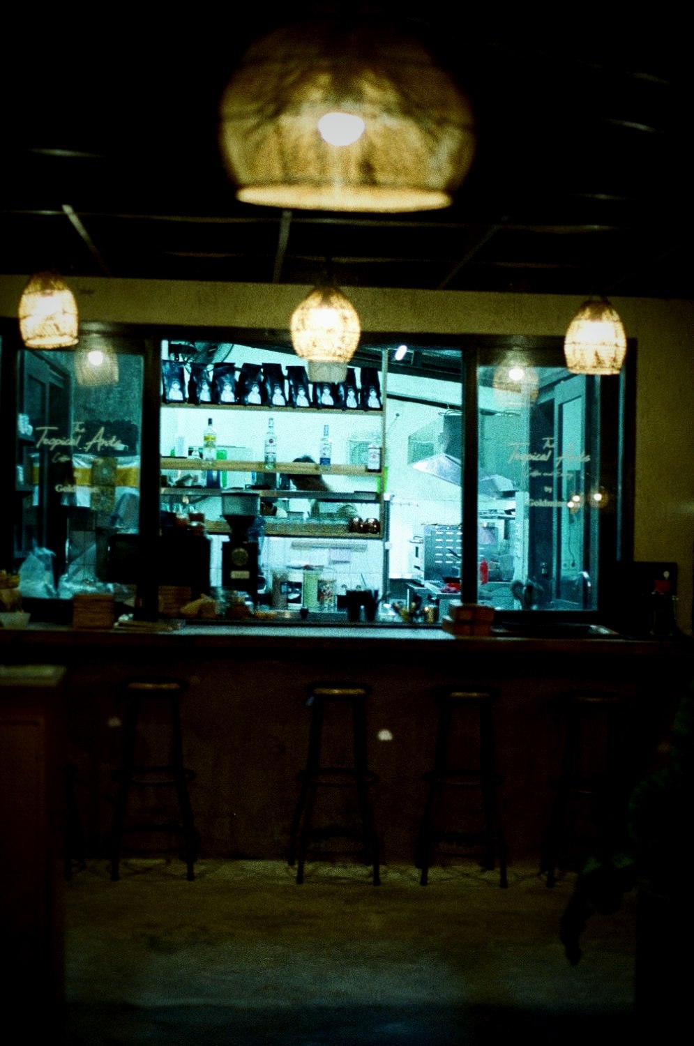 A dark bar at night, glowing pendant lamps