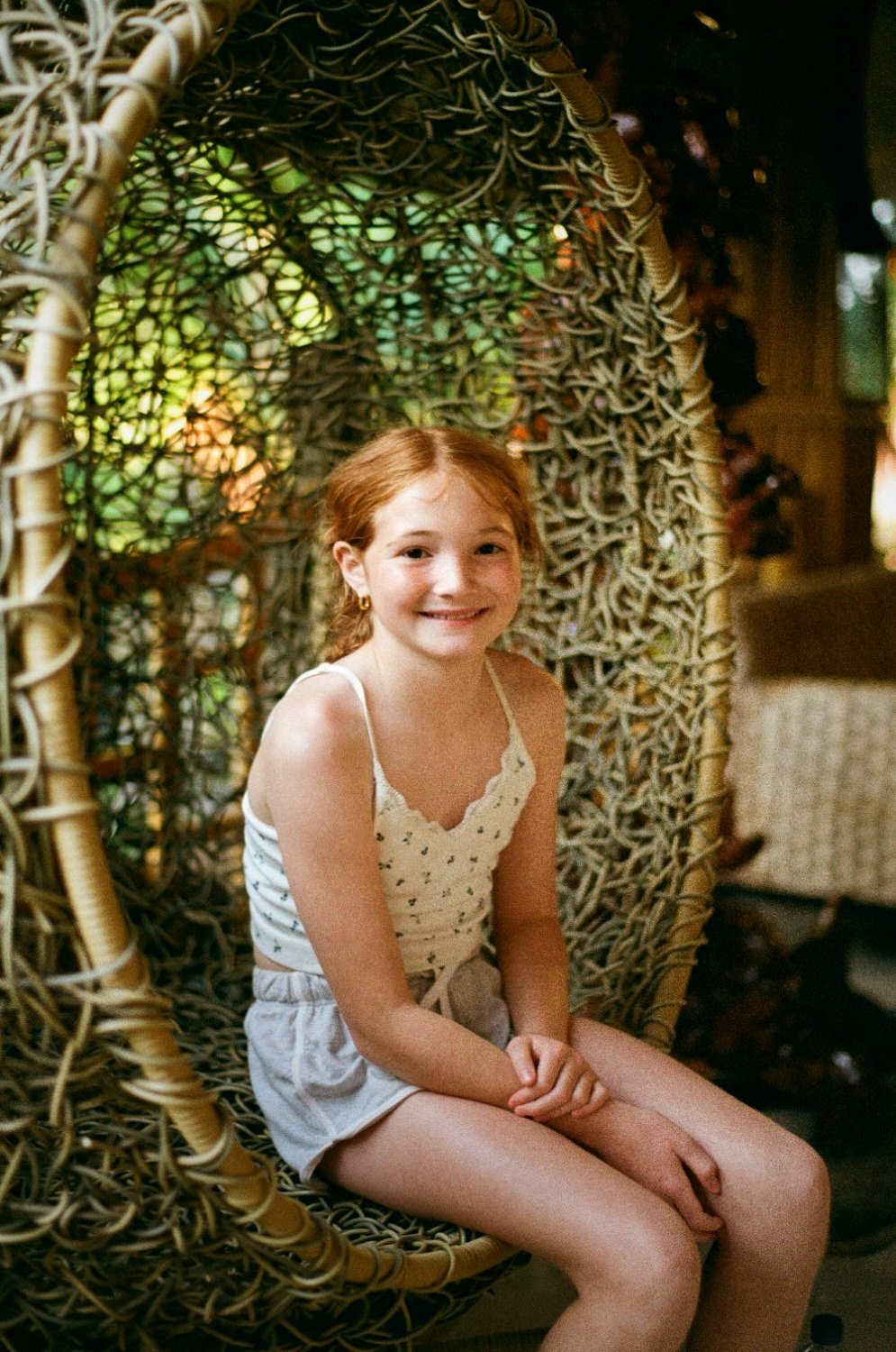 A red-haired girl in a hanging egg chair