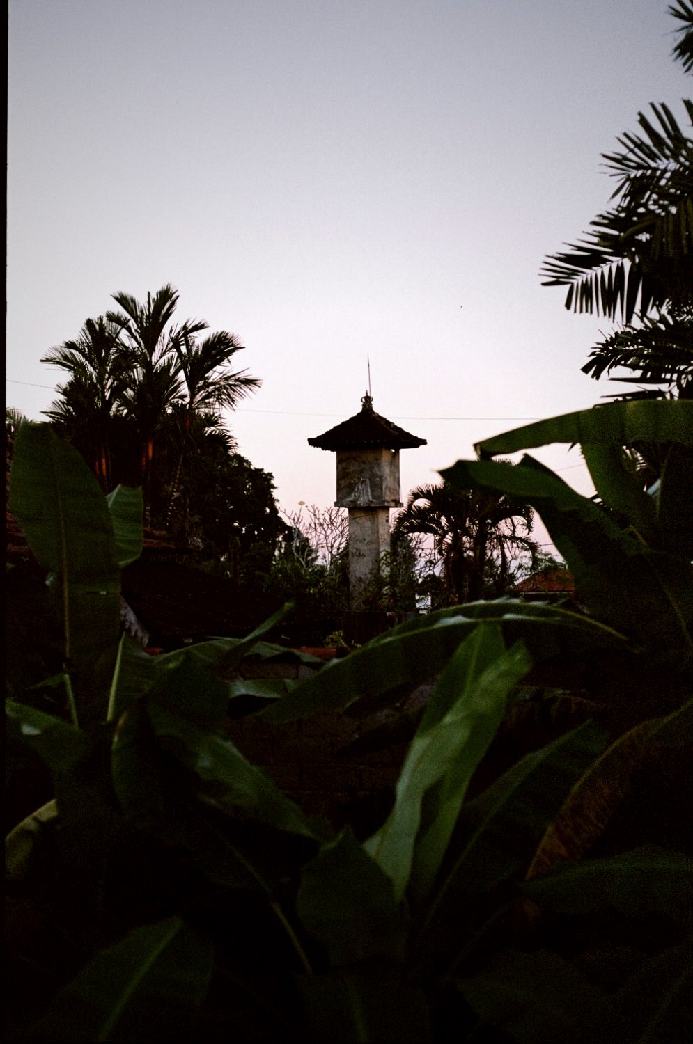 A Garuda shrine tower in silhouette at dusk